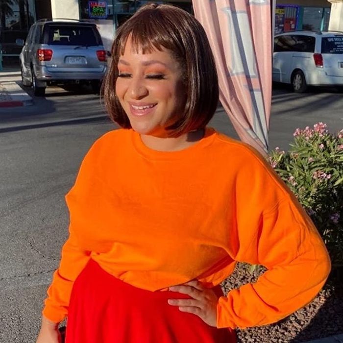 The reviewer is wearing a bright orange crewneck sweatshirt.