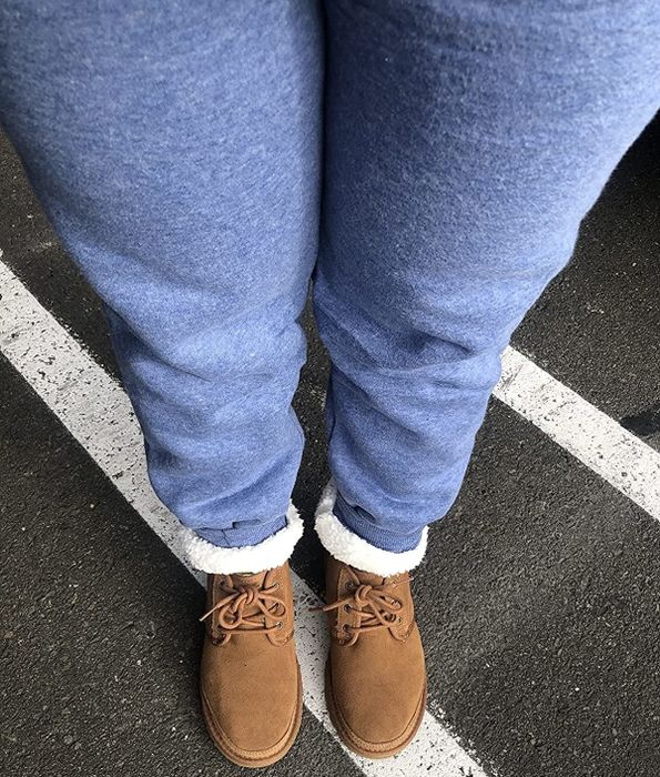 The reviewer is sporting blue joggers with the cuffs rolled up, showcasing the sherpa lining.
