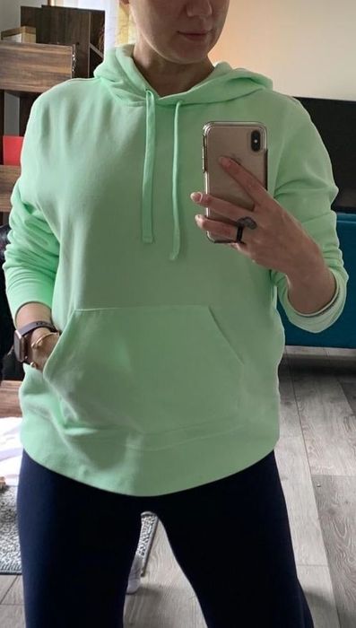A reviewer is pictured wearing the light green hoodie.