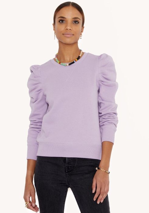 The model is wearing a lavender sweatshirt.