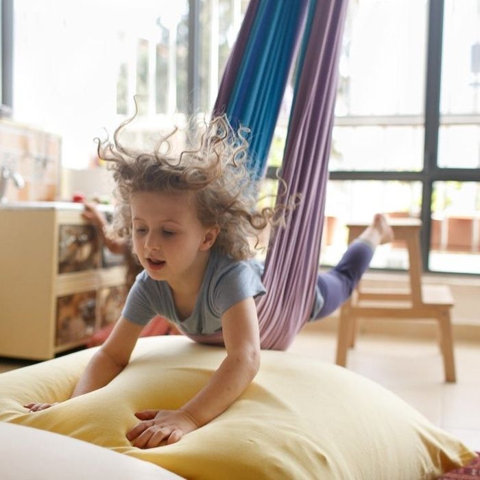 A different child swinging on their stomach as if flying, landing safely on a pile of soft pillows