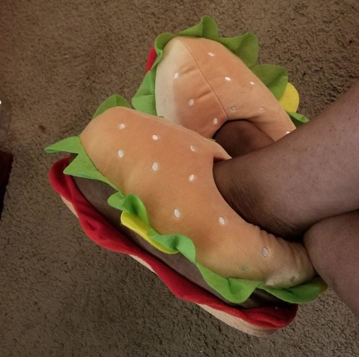 A reviewer wearing slippers that are cleverly designed to look like hamburgers, adding a fun touch to their cozy day.