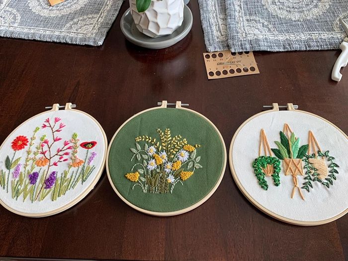 A reviewer’s three completed embroidery projects, all showcasing beautiful plant and flower themes.
