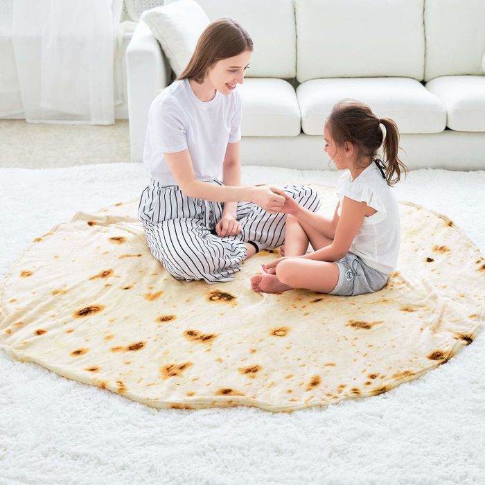 Two people lounging on a round tortilla blanket, fully immersed in its soft embrace.
