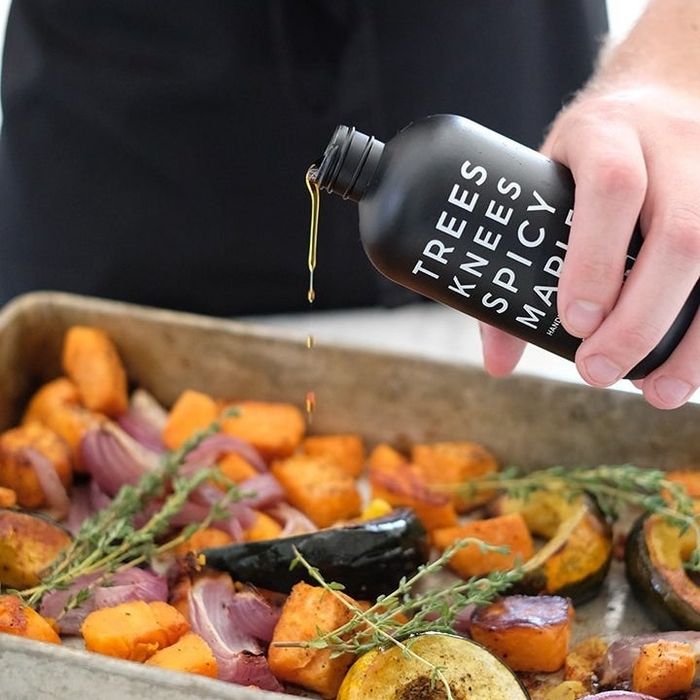 A hand drizzling spicy honey over roasted vegetables, enhancing their flavor with a sweet and spicy touch.