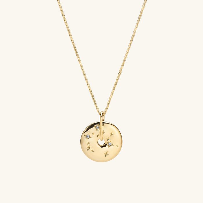 The gold pendant shaped like a donut, adorned with a constellation pattern, hanging gracefully from a chain.