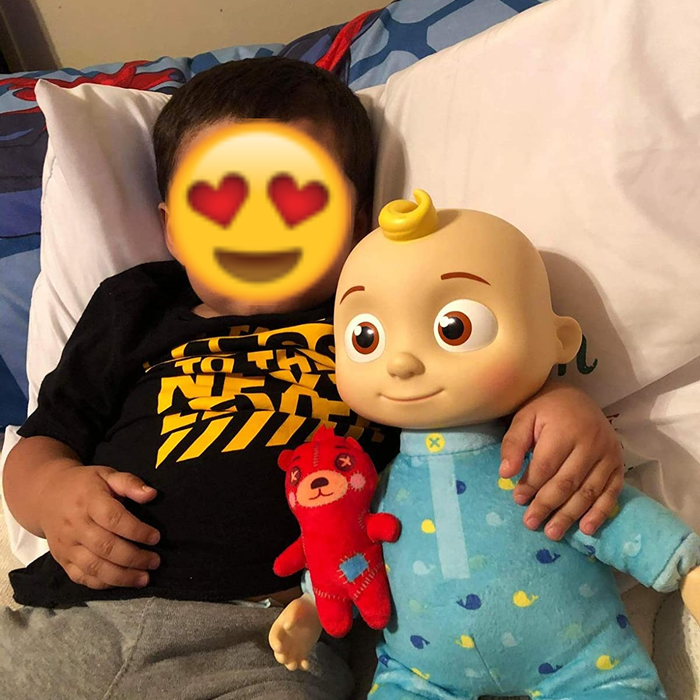 A reviewer’s child holding the Cocomelon doll in bed