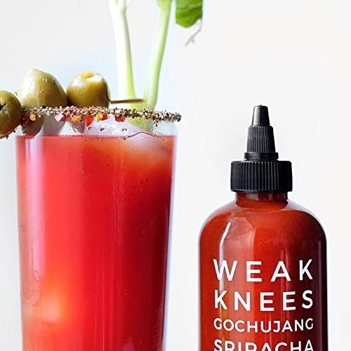 The sriracha sauce being poured onto the rim of a Bloody Mary glass, ready to add some extra heat to the drink.