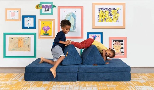 Two kids playing on the blue Nugget couch