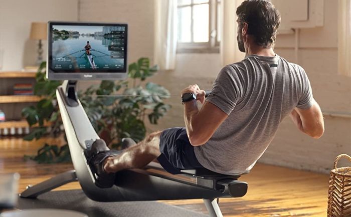 A model uses the rower while enjoying the immersive screen.