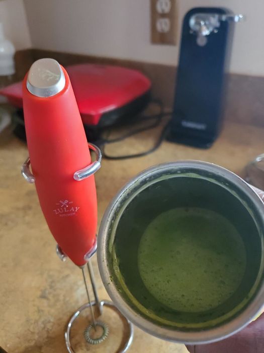 a reviewer's red frother placed next to a mug of matcha