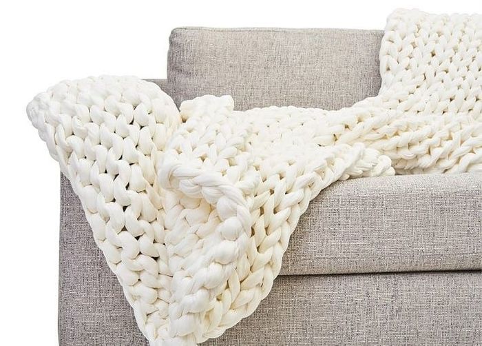 A cozy white cotton knit Bearaby blanket, draped over a sofa for ultimate relaxation.