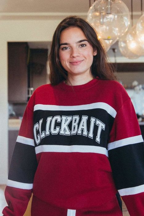 A woman sporting a red and black sweater with the word Clickbait written across it.