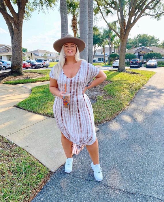 A reviewer sporting the pink tie-dye maxi dress, paired with sneakers and a hat for a casual, cool look.