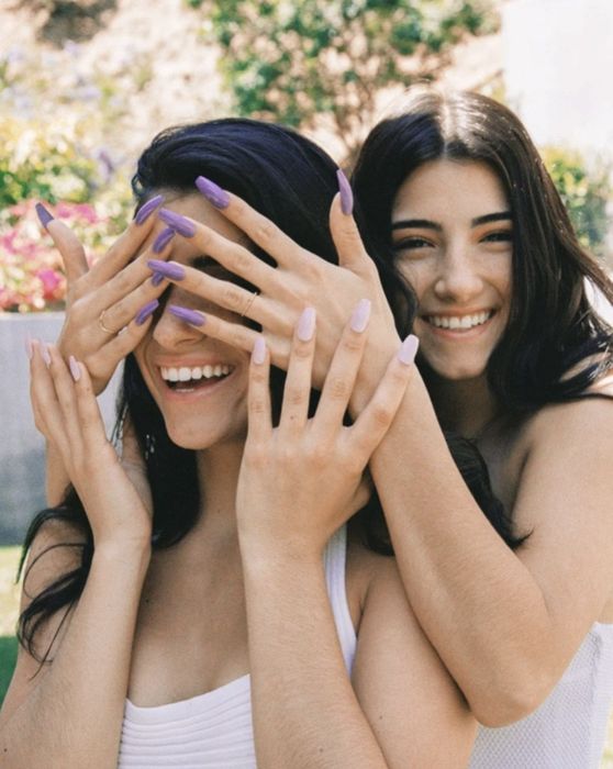 Charli playfully covers Dixie's eyes as she showcases her beautifully manicured nails.