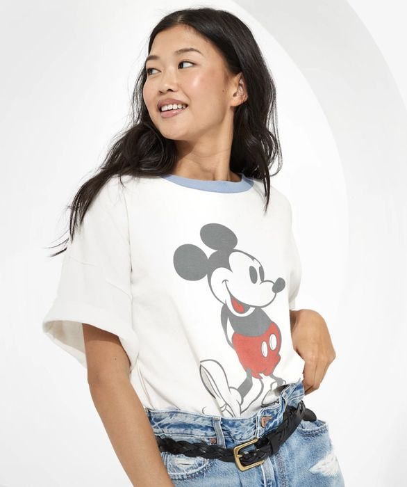 A model shows off a white t-shirt with a blue collar and a graphic of Mickey Mouse.