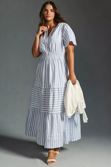A model is seen in the dress featuring blue and white stripes, creating a timeless look.