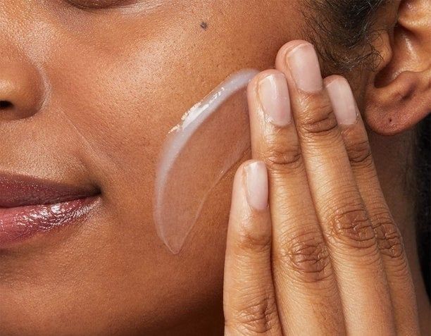 A model is applying the cleanser to their skin.
