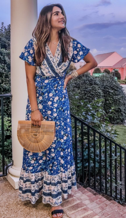 A reviewer wears the wrap dress in a deep blue shade, looking effortlessly chic as they model the look.