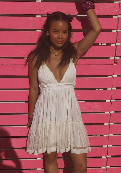 A reviewer in a beige patchwork mini dress