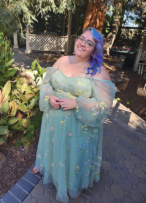 A reviewer in a long tulle gown adorned with embroidered flowers