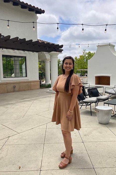 The reviewer is wearing a brown dress with a pair of sandals.