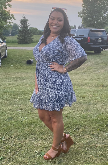 A reviewer sporting a dark blue dress adorned with a white and blue pattern