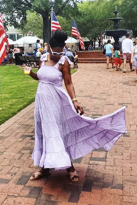 A reviewer in a purple maxi dress