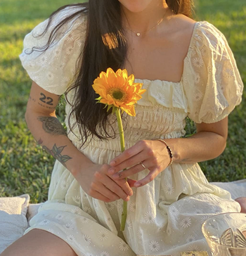 A reviewer wearing a puff-sleeve white square-neck dress with embroidered flowers