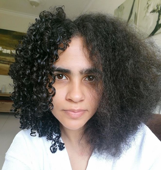 Reviewer demonstrating half of her hair curled using the brush, and the other half air-dried without it.
