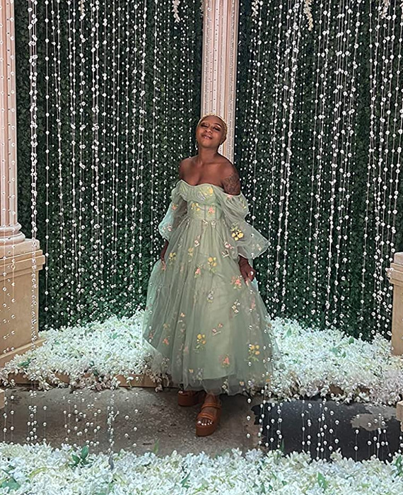 A reviewer in a long tulle gown adorned with embroidered flowers