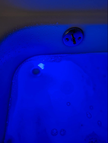 As the bath fizz dissolves, the blue light in the tub causes it to glow, creating a calming ambiance.