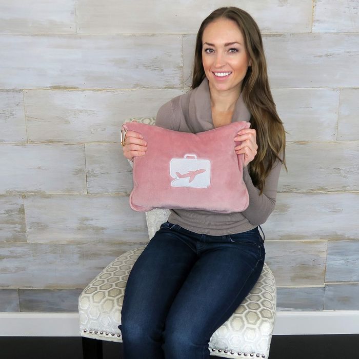 The pink pillow and blanket set neatly stored in a fluffy pink travel pouch.