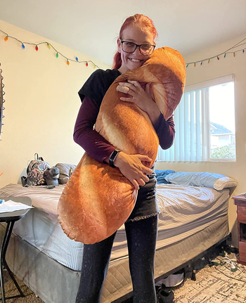 Reviewer holding a large baguette-shaped pillow
