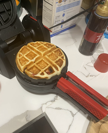 A waffle cooking in a waffle maker.