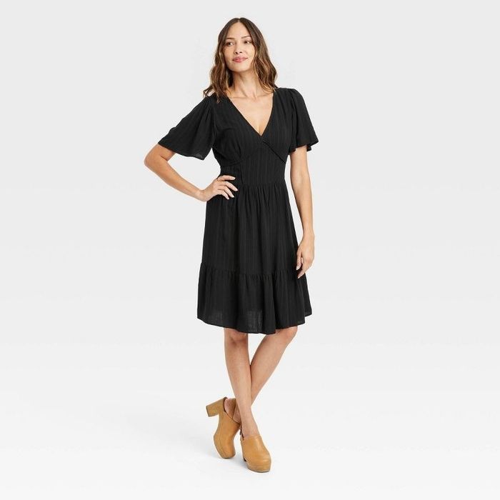 A model rocking the black dress paired with clogs