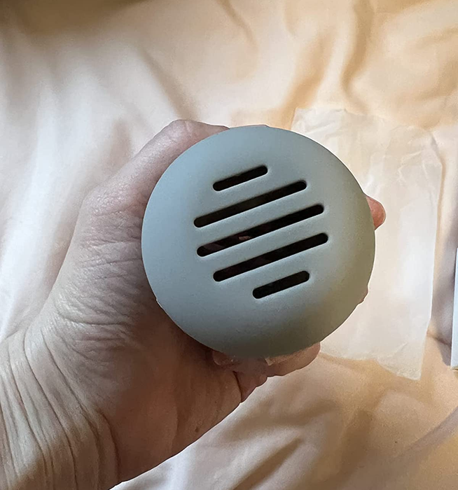A reviewer's photo of the makeup sponge holder in a soft light grey color.
