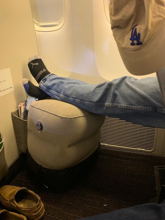 a reviewer showing the footrest inflated and their feet comfortably resting on it during a flight