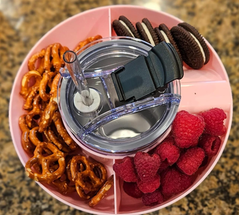 A pink bowl seen from above, divided into four sections for different snacks