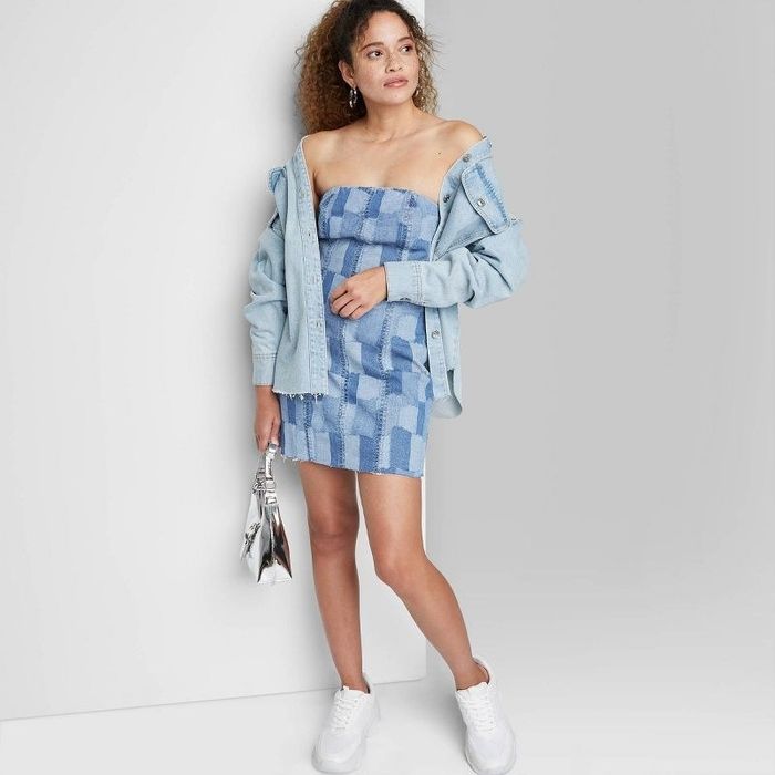 A model wearing a denim shirt layered over the indigo patchwork dress