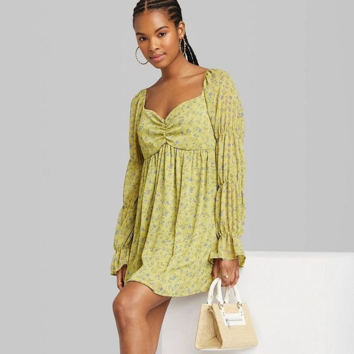 A model showcasing the dress in green floral with a stylish handbag