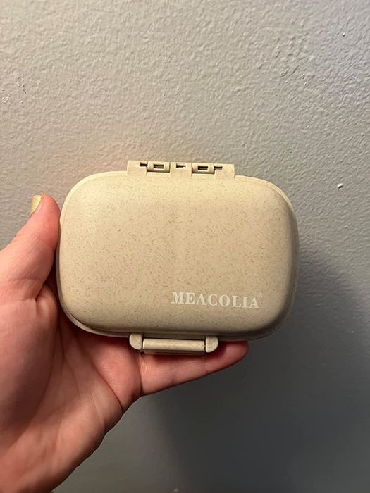 The same reviewer holding their pill organizer, now closed and ready for use.