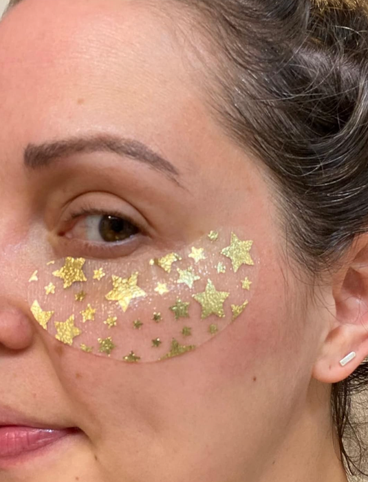A reviewer with a transparent eye mask adorned with glittering gold stars beneath their eyes.