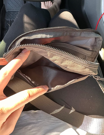 The reviewer unzips the fanny pack, revealing the various compartments inside.
