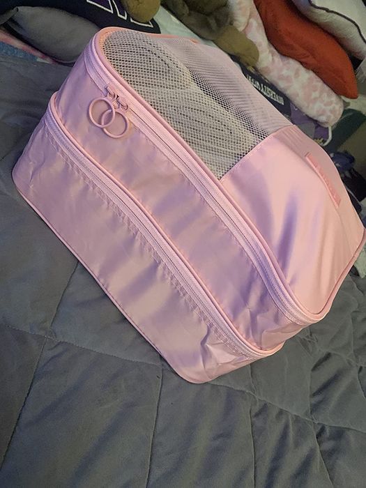 A reviewer shows the pink shoe bag, packed with shoes, emphasizing its practical and stylish design.