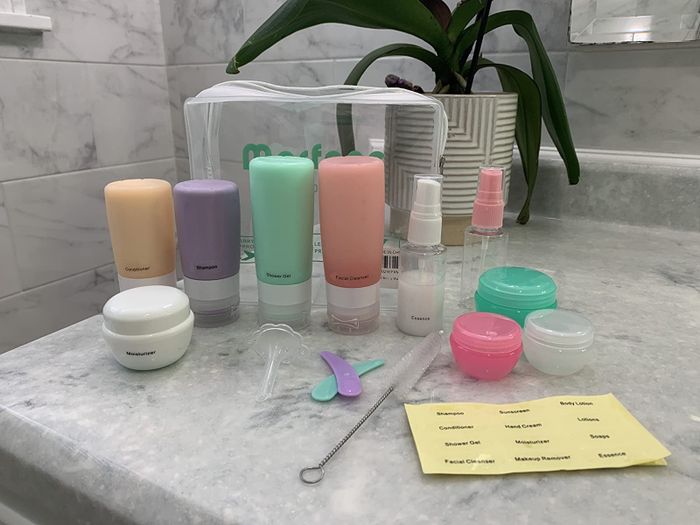 A reviewer's photo showcasing a set of travel-sized containers, bottles, and accessories.