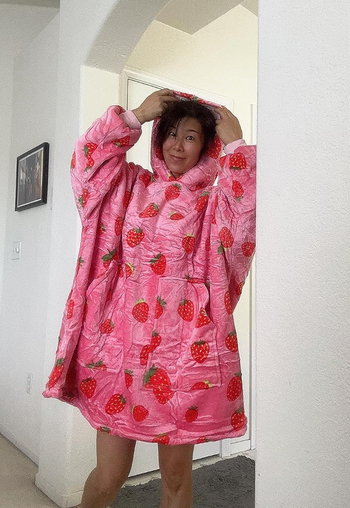 A reviewer wearing a sweater that reaches down to their knees, demonstrating its length.