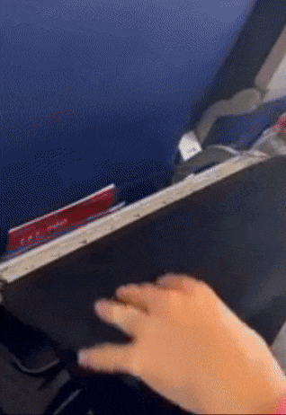 The model slides a black cover over a tray, which features pockets to store a snack, a laptop, and other devices.