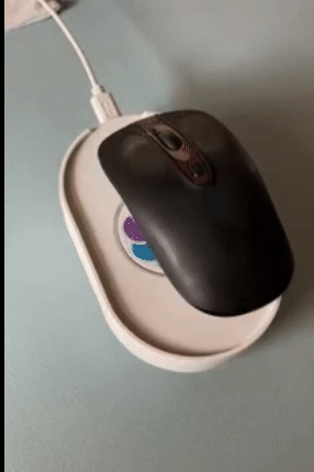 A mouse on a sleek, white oval-shaped device that subtly moves the mouse to keep it active.