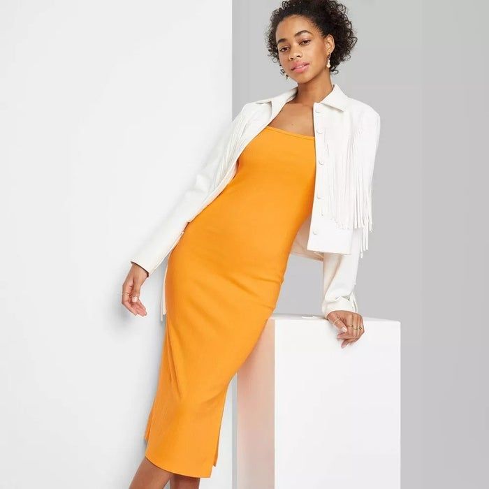 model wearing a yellow sleeveless bodycon dress paired with a cropped white fringe jacket